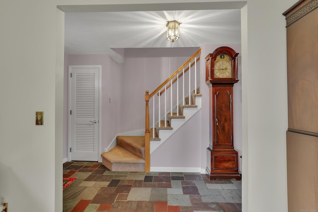 staircase with stone tile floors and baseboards