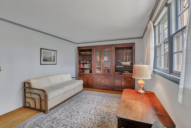 living area with light wood-style floors, baseboards, and ornamental molding