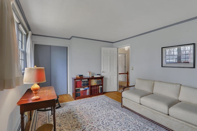 living area with crown molding, a baseboard heating unit, and wood finished floors
