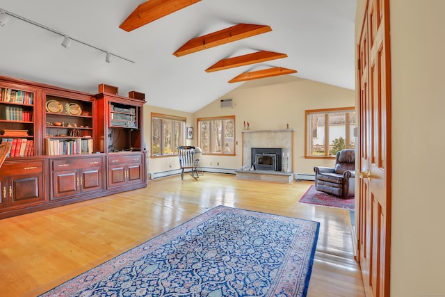 living room featuring lofted ceiling with beams, track lighting, baseboard heating, wood finished floors, and a tile fireplace