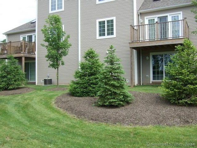 view of property exterior featuring a lawn, a balcony, and central AC