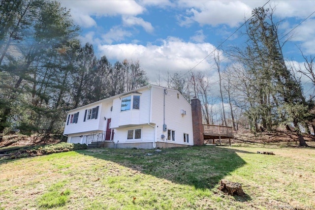 back of property featuring a chimney, an attached garage, a yard, and a deck