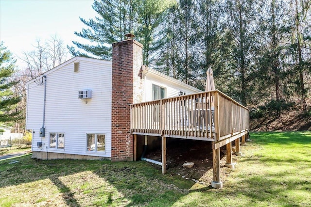 rear view of property with a chimney, a wooden deck, and a lawn