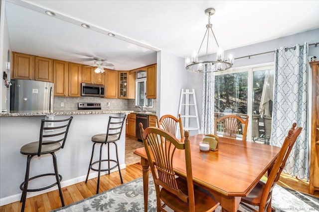 dining area with light wood-type flooring and ceiling fan with notable chandelier