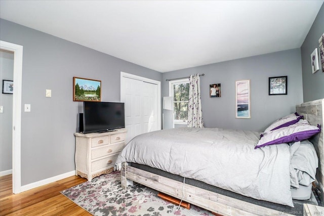 bedroom with baseboards, wood finished floors, and a closet