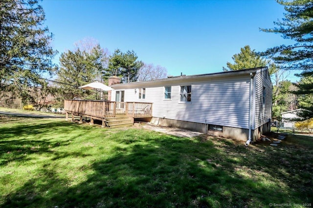 rear view of house with a yard, a chimney, and a deck