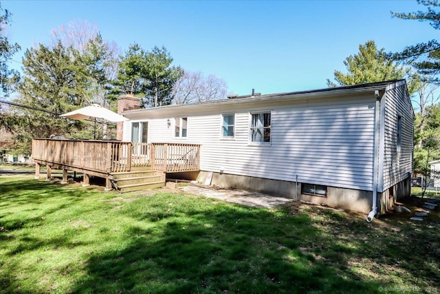 back of house featuring a lawn, a chimney, and a wooden deck