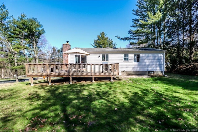 back of property featuring a lawn, a chimney, and a deck