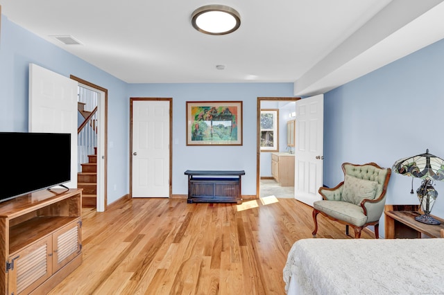 bedroom featuring light wood-type flooring, baseboards, visible vents, and a sink