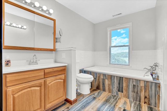 full bathroom with a garden tub, wood finished floors, vanity, toilet, and visible vents