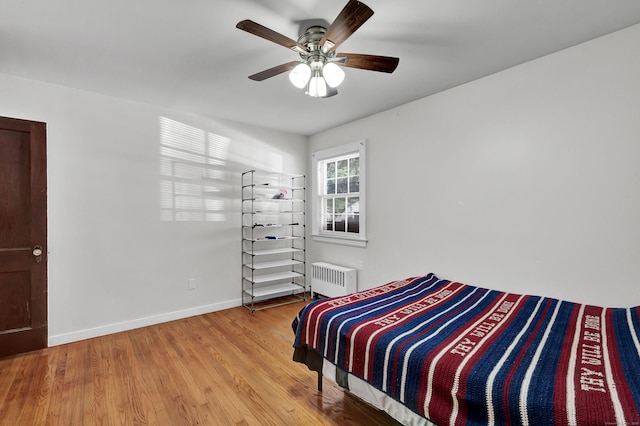 bedroom featuring radiator, wood finished floors, baseboards, and ceiling fan