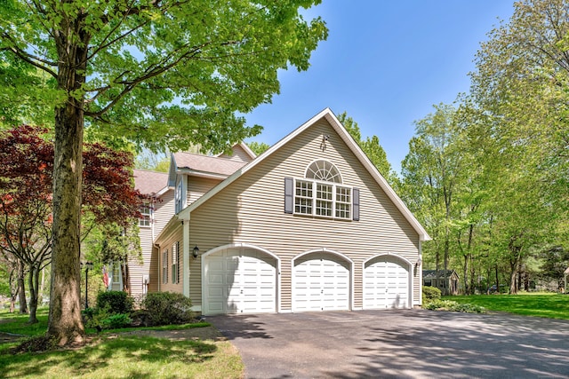 view of side of property with driveway, a garage, and roof with shingles