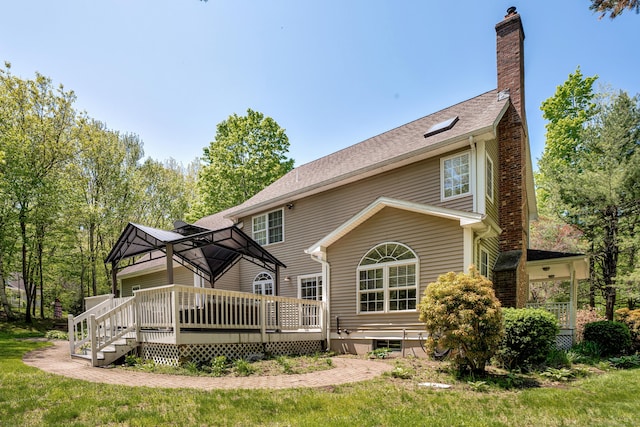 back of house with a chimney, a deck, a gazebo, a lawn, and roof with shingles