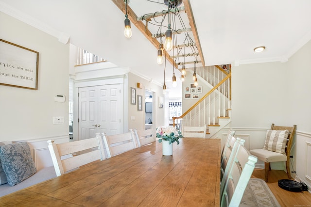 dining room with ornamental molding, stairway, a wainscoted wall, wood finished floors, and a decorative wall