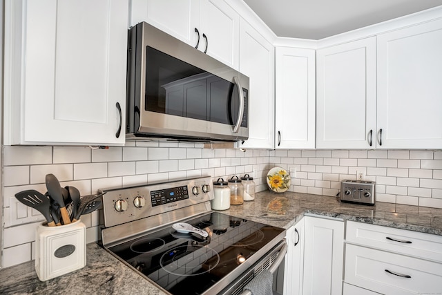 kitchen with stainless steel appliances, white cabinets, decorative backsplash, and dark stone countertops