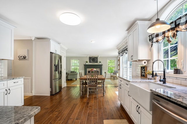 kitchen with stainless steel appliances, a sink, dark wood finished floors, open floor plan, and ornamental molding