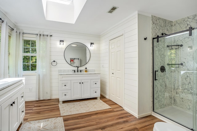 full bathroom featuring a marble finish shower, vanity, wood finished floors, and a skylight