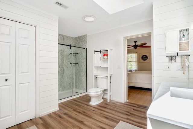 ensuite bathroom featuring a stall shower, wood finished floors, toilet, and vanity