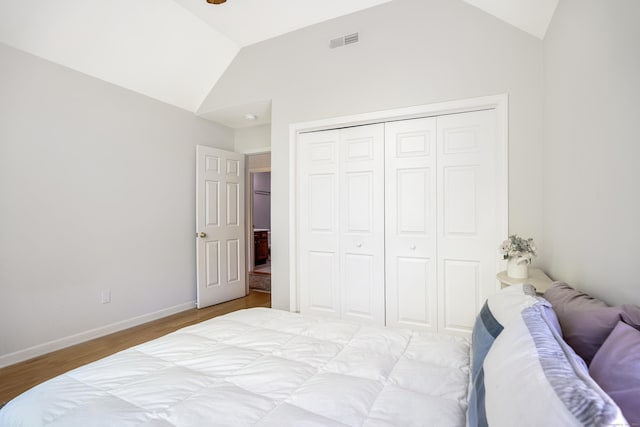 bedroom featuring vaulted ceiling, wood finished floors, a closet, and baseboards