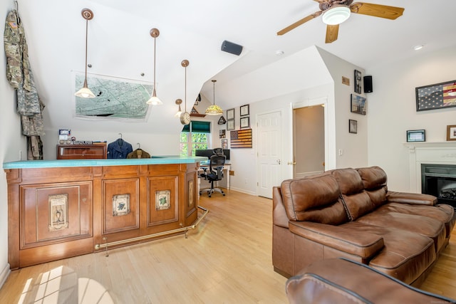 living area featuring light wood-style floors, a ceiling fan, a desk, lofted ceiling, and baseboards