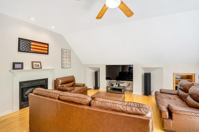 living area with light wood-style floors, a fireplace, lofted ceiling, ceiling fan, and baseboards