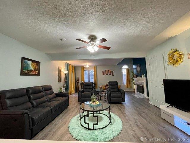 190 Main St Apt D, Manchester, CT 06042 - living room with a textured ceiling, wood finished floors, a ceiling fan, and a fireplace with flush hearth