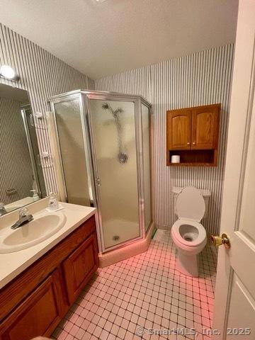 190 Main St Apt D, Manchester, CT 06042 - full bathroom featuring wallpapered walls, a shower stall, vanity, tile patterned flooring, and toilet