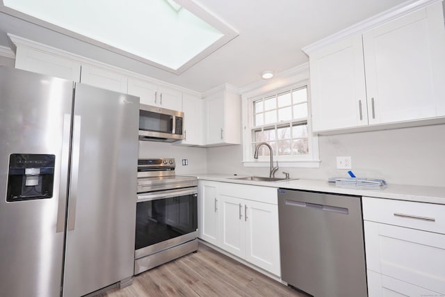 kitchen featuring crown molding, white cabinets, a sink, stainless steel appliances, and light countertops