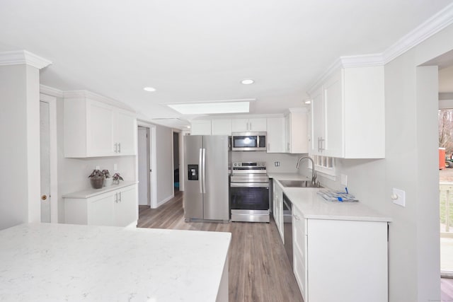 kitchen with white cabinetry, a sink, appliances with stainless steel finishes, light wood-style floors, and light countertops