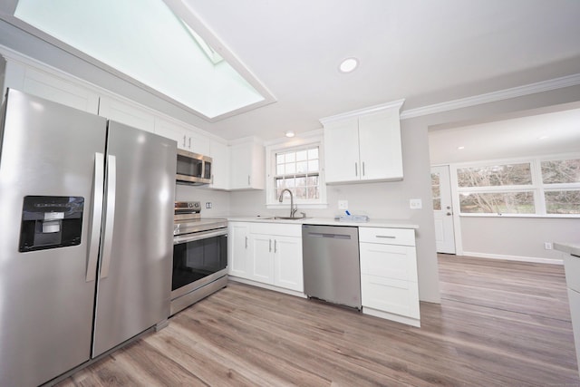 46 Sperry Dr, Guilford, CT 06437 - kitchen featuring appliances with stainless steel finishes, light countertops, ornamental molding, white cabinets, and light wood-style flooring