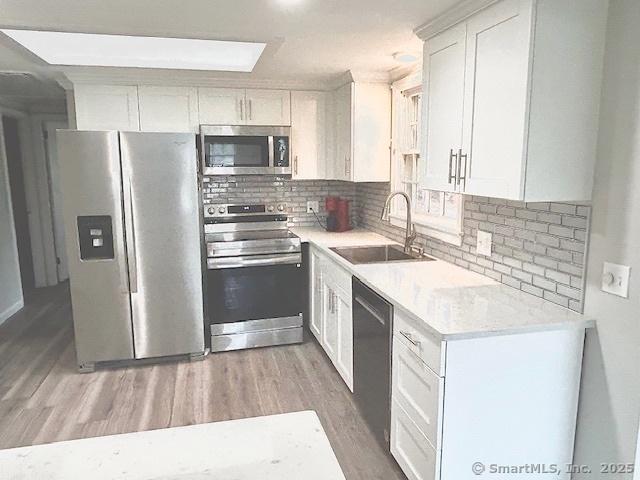 46 Sperry Dr, Guilford, CT 06437 - kitchen with stainless steel appliances, light wood-type flooring, backsplash, and white cabinetry