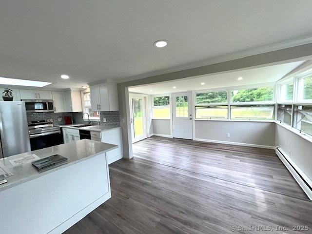 46 Sperry Dr, Guilford, CT 06437 - kitchen with appliances with stainless steel finishes, a baseboard heating unit, light countertops, dark wood-style flooring, and decorative backsplash