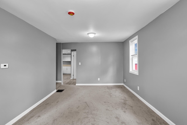 carpeted spare room featuring baseboards