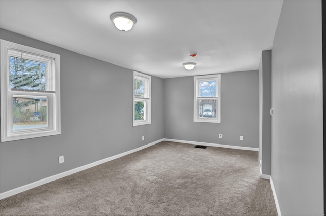 carpeted empty room featuring visible vents and baseboards