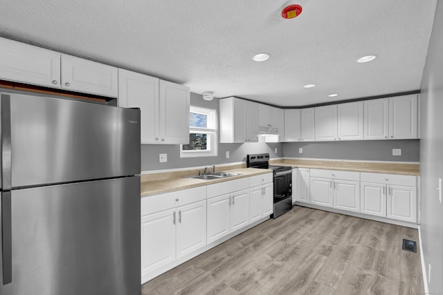 kitchen with a sink, stainless steel appliances, a textured ceiling, recessed lighting, and light countertops