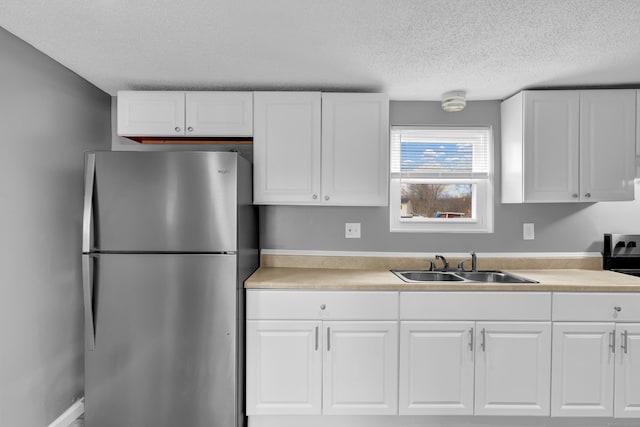 kitchen with freestanding refrigerator, light countertops, a textured ceiling, and a sink