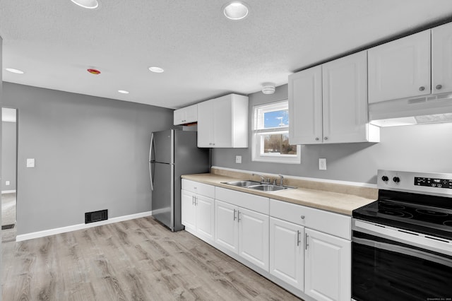 kitchen with a sink, a textured ceiling, visible vents, under cabinet range hood, and appliances with stainless steel finishes