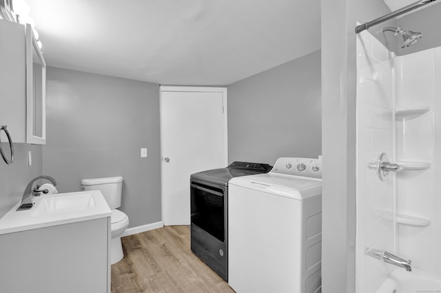 laundry room with a sink, laundry area, washer and clothes dryer, and light wood finished floors