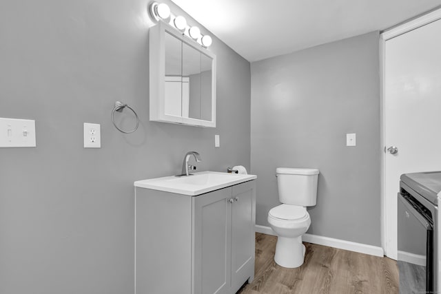 bathroom with toilet, baseboards, vanity, and wood finished floors