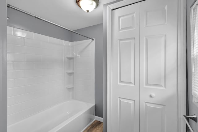 bathroom with wood finished floors, baseboards, and washtub / shower combination