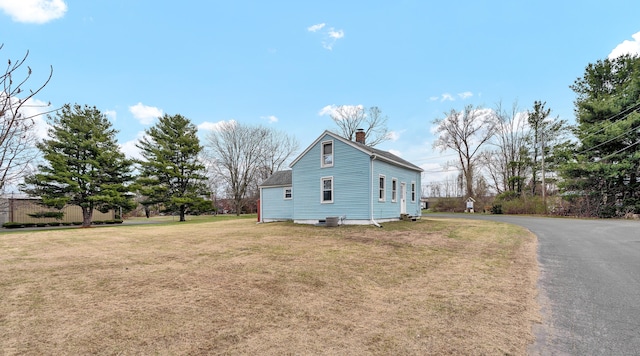 view of property exterior with a chimney and a lawn