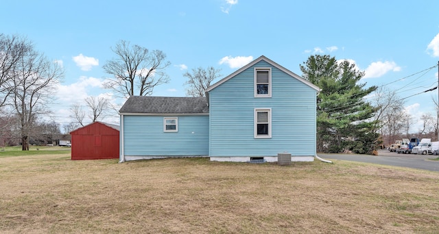 exterior space with roof with shingles, a storage shed, an outbuilding, and a lawn