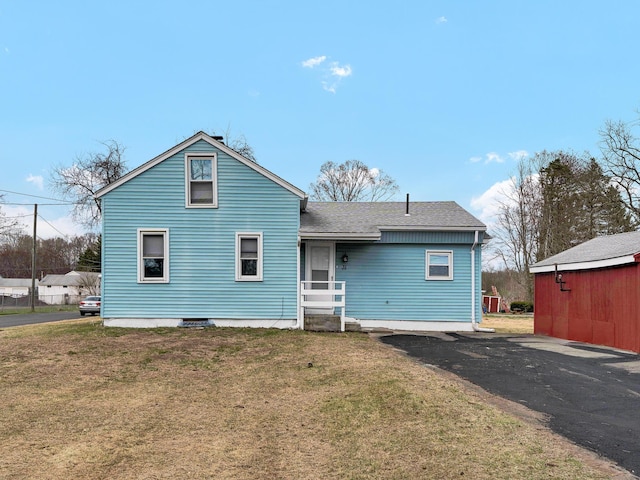 back of property with a yard and roof with shingles