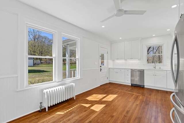 34 Power House Rd, Montville, CT 06382 - kitchen featuring radiator heating unit, tasteful backsplash, wood finished floors, appliances with stainless steel finishes, and white cabinetry