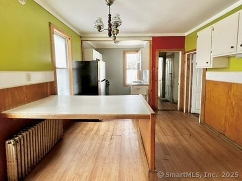 kitchen featuring plenty of natural light, radiator, a peninsula, and freestanding refrigerator
