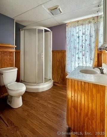 full bathroom with a shower stall, toilet, a wainscoted wall, and wood finished floors