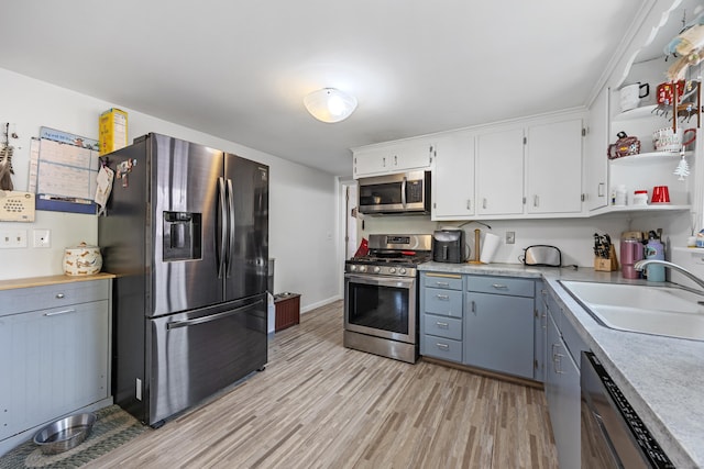 kitchen featuring stainless steel appliances, open shelves, light countertops, white cabinets, and light wood-type flooring