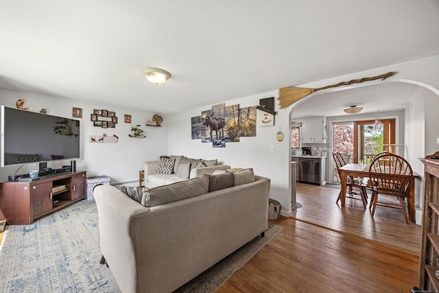 living area featuring arched walkways, wood finished floors, and baseboards