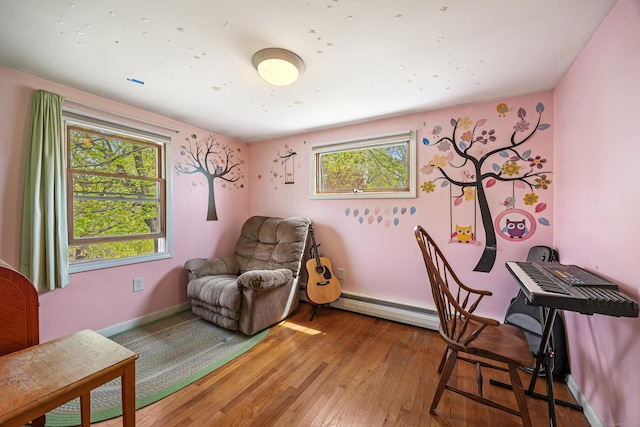 living area with baseboard heating, baseboards, and hardwood / wood-style flooring