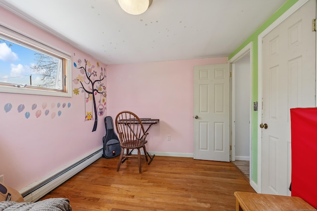 sitting room featuring a baseboard radiator, light wood-type flooring, and baseboards